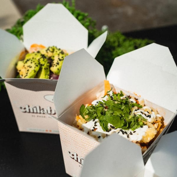 Two Chilabox takeout containers filled with Mexican food, one with avocado and the other with cilantro.