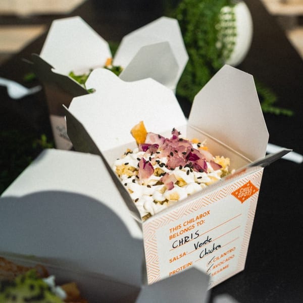 A Chilabox with chicken, verde salsa, cilantro, avocado, and sesame seeds, labeled for Chris.