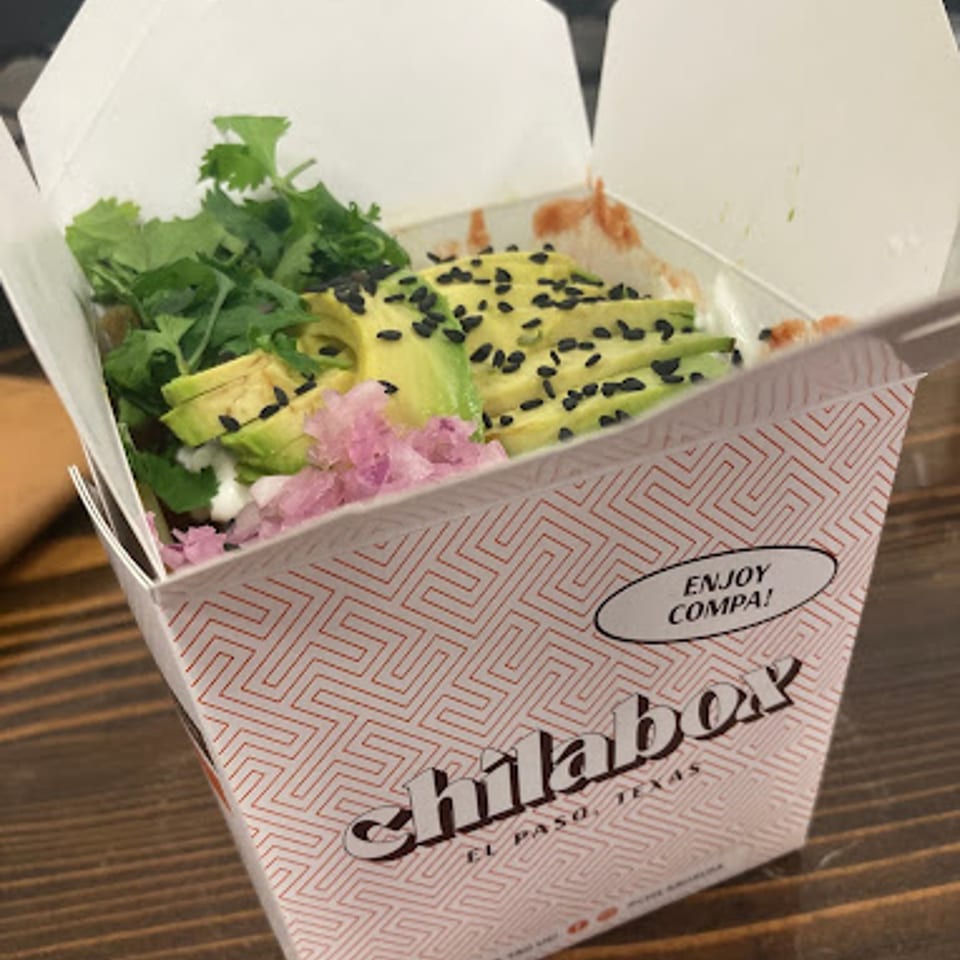 Chilabox takeout container filled with avocado, cilantro, pickled onions, and black sesame seeds.